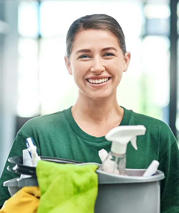 Büroreinigung - lächelnde junge Frau in grünem T-Shirt mit einem grauen Eimer vor sich mit Reinigungsutensilien in der Hand - Clean Team Reinigung von Büros