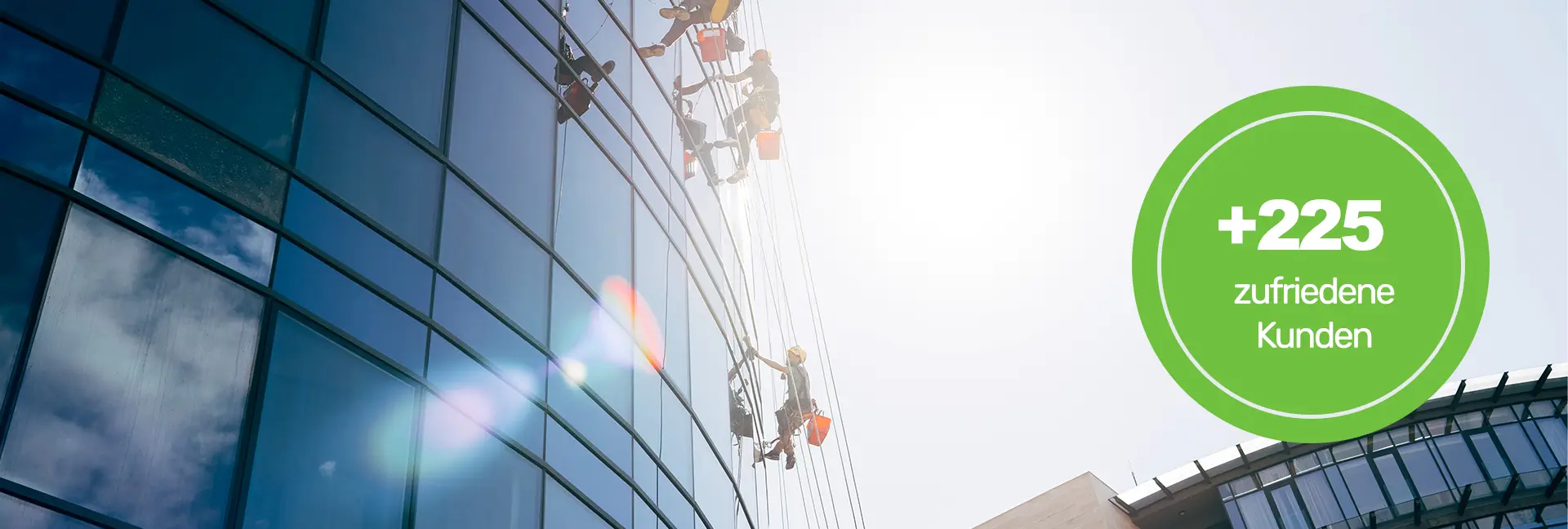 Gebäudereinigung Köln - Zwei Reinigungskräfte mit roten Putzeimern seilen sich aus großer Höhe an einem Bürogebäude ab und reinigen die Fensterfront von außen - Clean Team